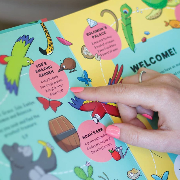 Photograph of someone pointing at an image inside of a Seek and Find board book